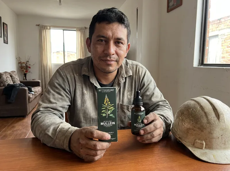 Trabajador de construcción colombiano en su casa con el frasco y la caja de las gotas