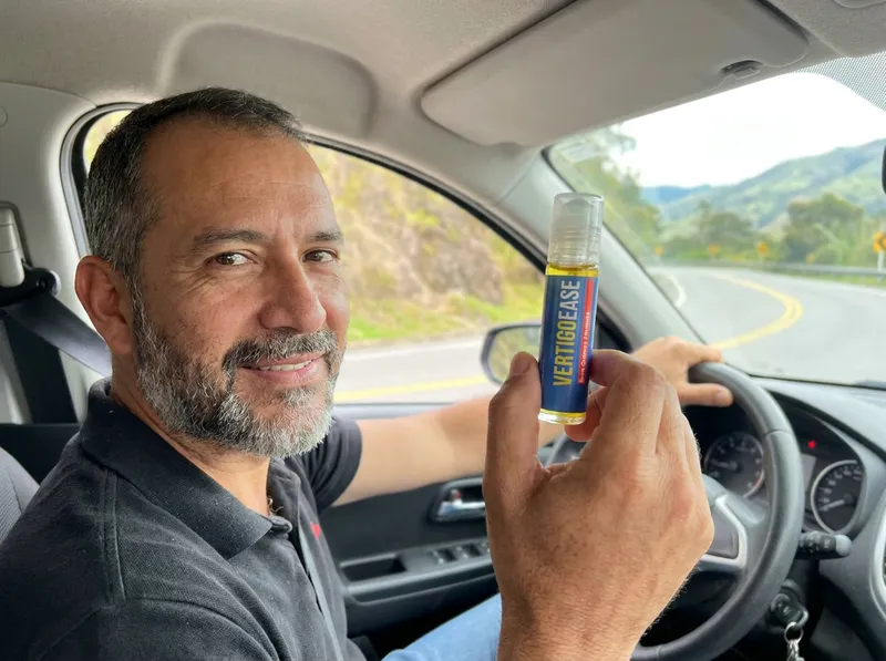 Hombre en su carro con el roll-on Vertigo Ease en la mano antes de arrancar